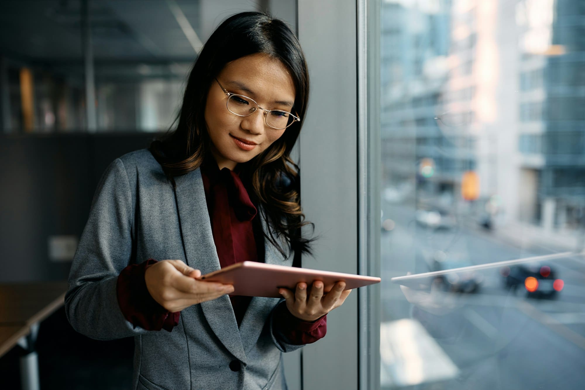 Asian female executive using digital tablet by the window.