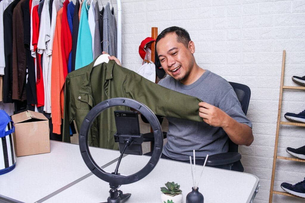 Asian male entrepreneur sell cloth product online on social media live streaming use smartpho