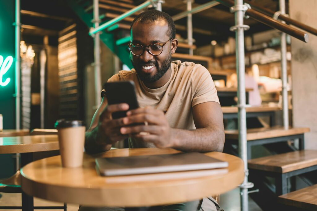 , cheerful hipster guy with modern cellular technology enjoying web chatting in social media