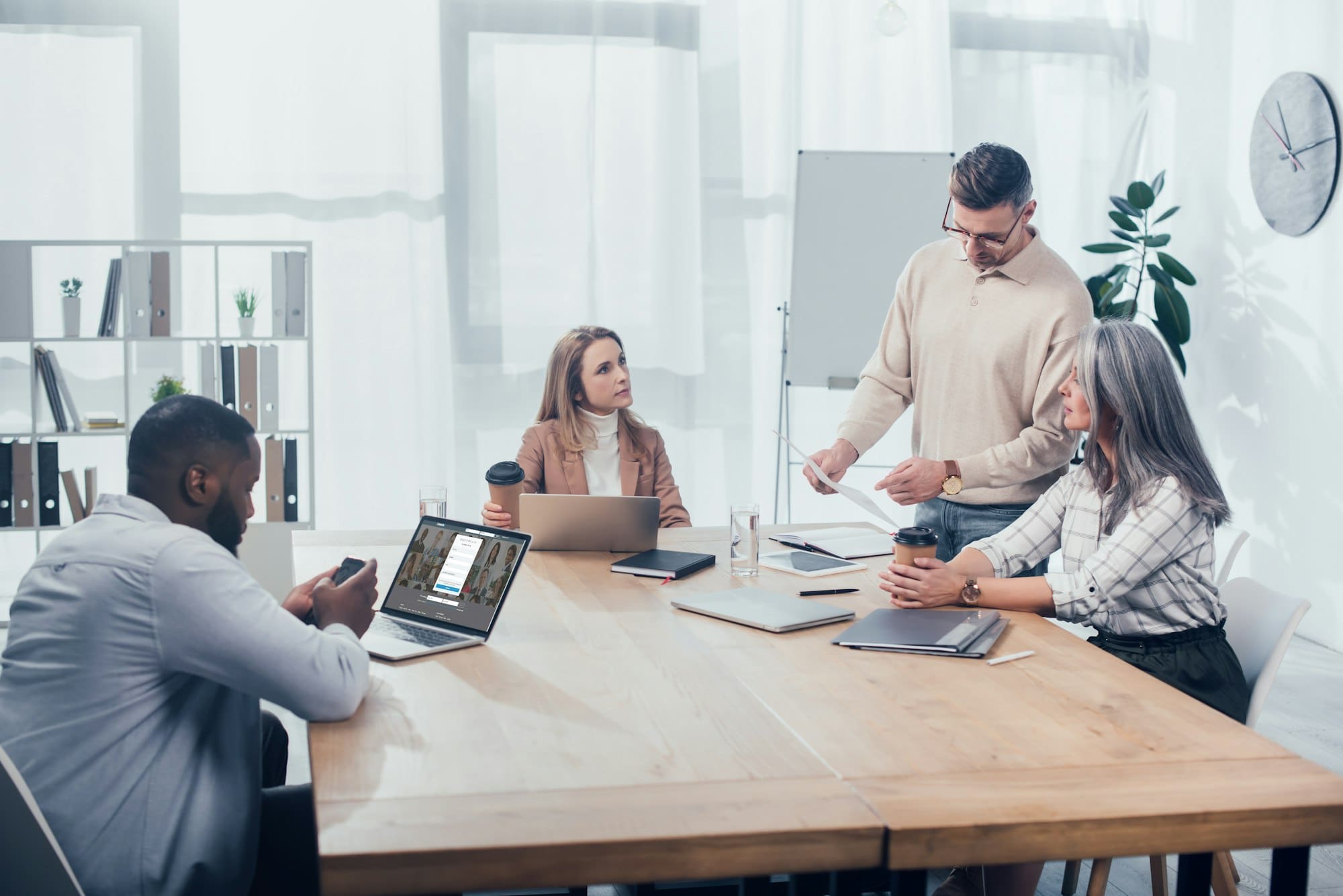 KYIV, UKRAINE - DECEMBER 6, 2019: colleagues doing paper work and african american man using