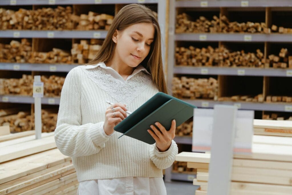 Woman with tablet in a timber and lumber warehouse. Product acceptance and quality control