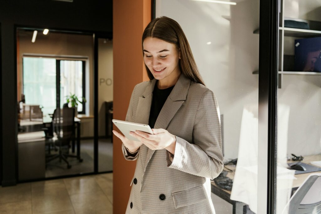 Smartly dressed businesswoman using a tablet in a modern office setting, focused and engaged.