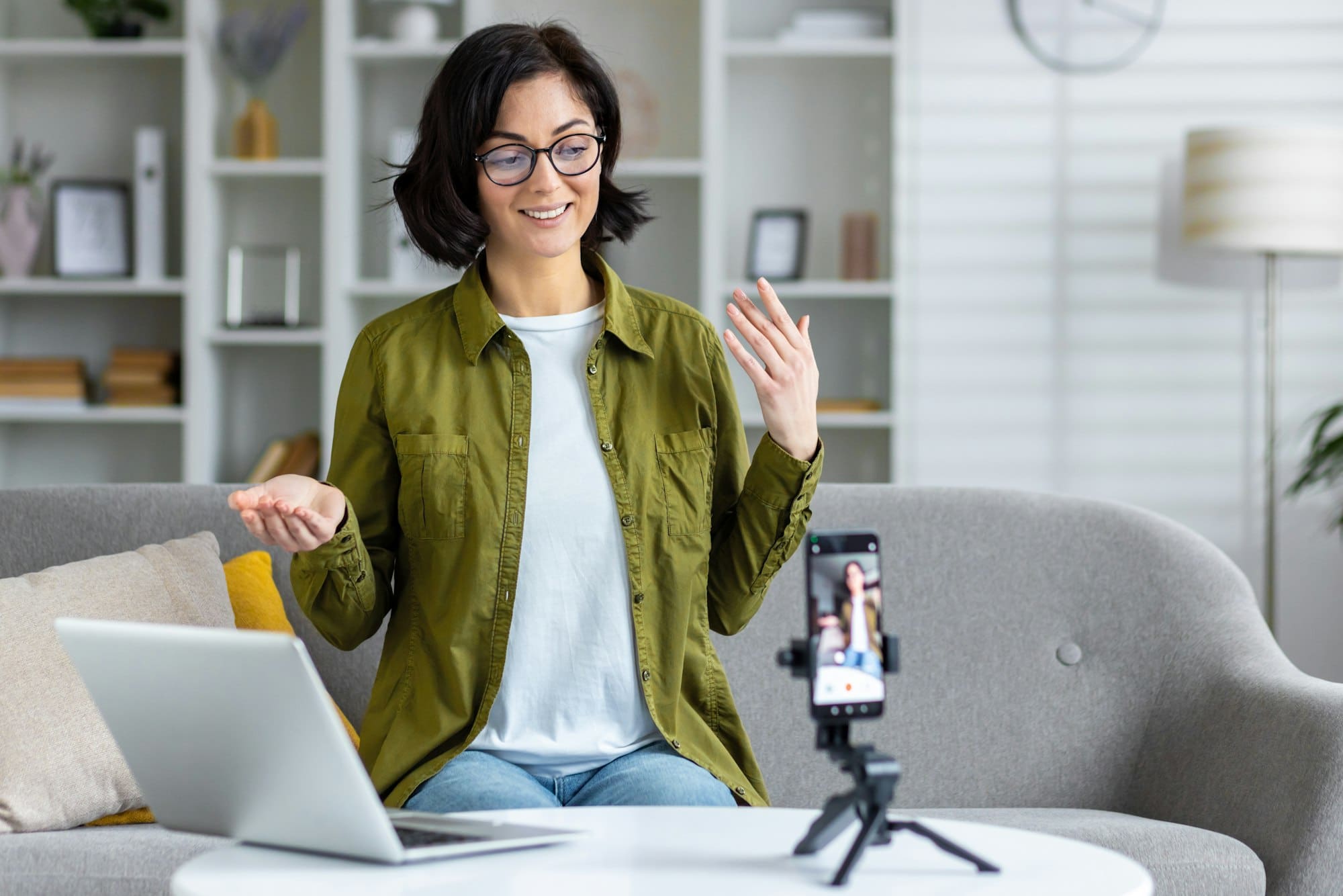 Professional woman creating content for online audience with smartphone and laptop