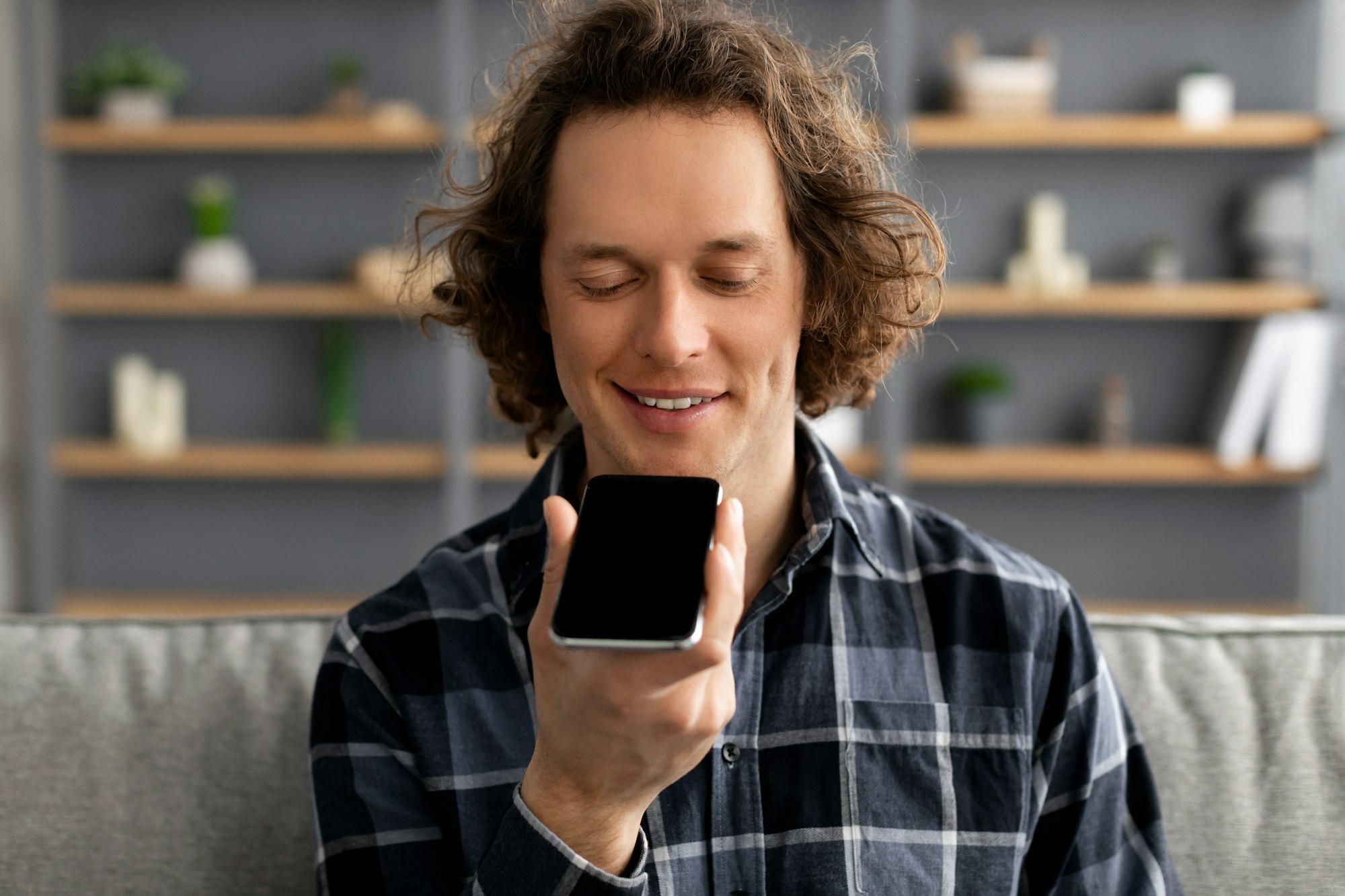 Guy Using Voice Assistant On Mobile Phone Sitting At Home