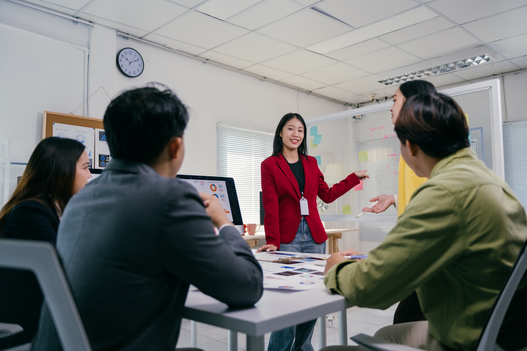Asian businesswoman leading meeting with team in modern office discussing marketing strategy