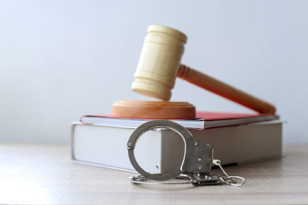 Judge gavel on a law book with metal handcuffs.